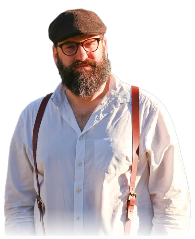 Jonathan Shubs, standing outdoors in warm light, wearing a cap and a white shirt
